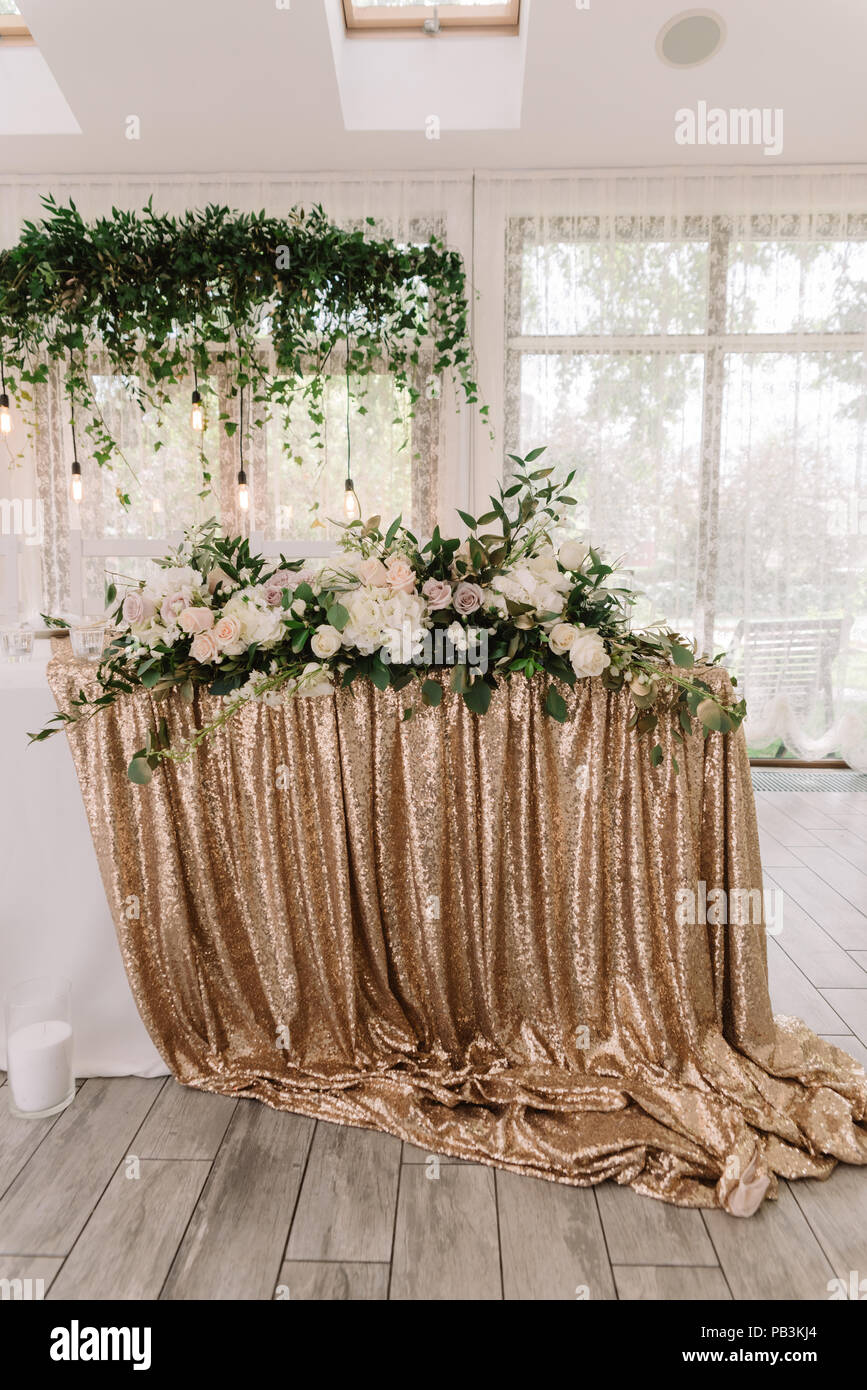 Tabella di classe di sposi su un matrimonio solennità. Il panno dorato su una tabella di nozze e un sacco di bella floristics di nozze Foto Stock