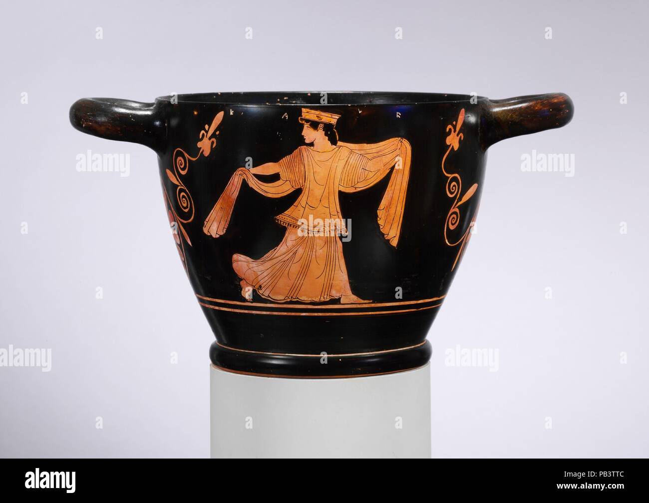 Skyphos in terracotta (deep bicchiere). Cultura: greco, soffitta. Dimensioni: H. con maniglie 5 13/16 in. (14,8 cm); larghezza con maniglie 10 15/16 in. (27,8 cm); diametro del recipiente 7 1/4 in. (18,4 cm). Data: ca. 470 A.C.. Complementare, Dionysos retromarcia, Arianna durante il sesto e quinto secolo A.C. Dionysos è indicato solitamente come una matura barbuto dio indossando un lungo chiton e mantello. Qui egli ha una banda di tessuto e una corona di foglie di vite intorno alla sua testa. Egli ha spesso porta un thyrsos, una levetta di finocchio e rabboccato con foglie d'edera. Sul skyphos, persegue la sua moglie, Arianna. Con una singola figura su ogni sid Foto Stock