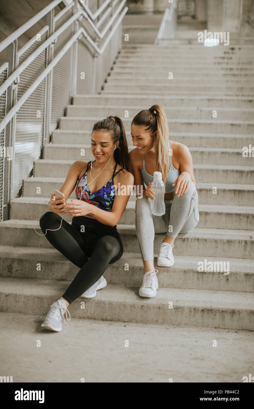 Due guide femmina cerca su smart phone un riposo dopo un po' di jogging nel envionment urbana Foto Stock