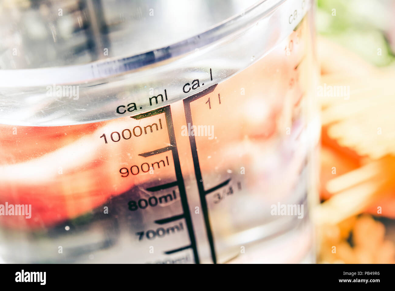 1000 ml - ccm di acqua in una coppa di misurazione circondato dalle tagliatelle, cipolla, carote e spezie Foto Stock