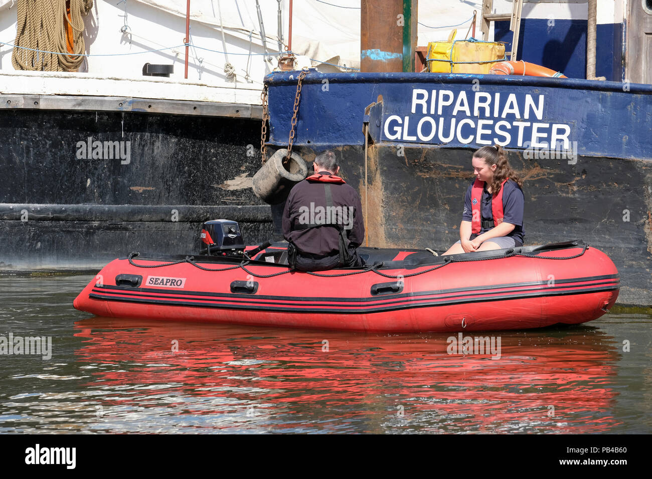 Canal draga rivierasche ormeggiata in Gloucester docks. Barca di sicurezza accanto a. Foto Stock