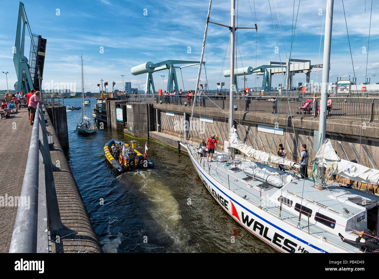 Uno yacht rende il modo attraverso i cancelli di blocco a Cardiff Barrage nella Baia di Cardiff Galles del Sud, Regno Unito sotto un cielo di estate blu. Foto Stock