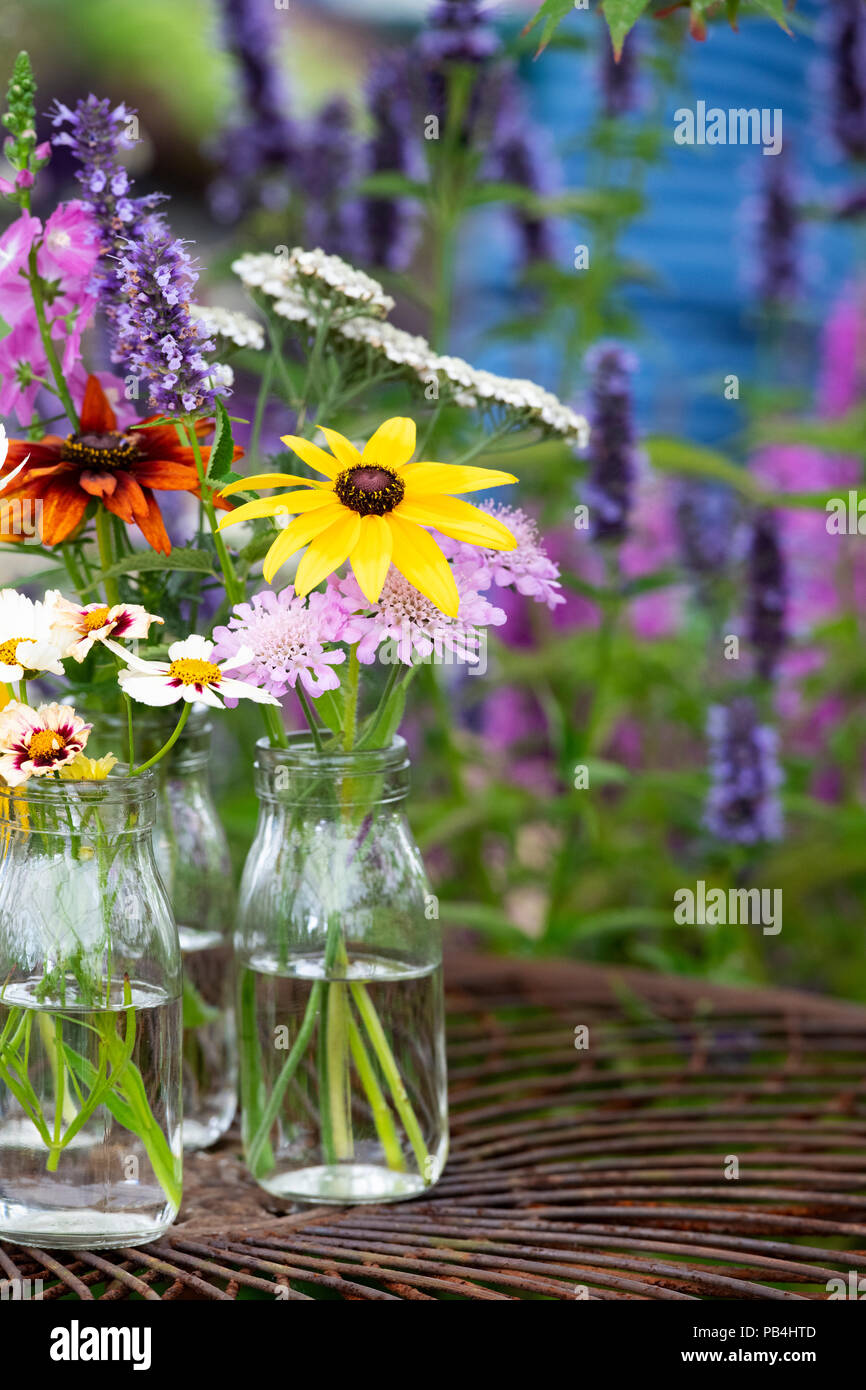 Fiori in bottiglie di vetro su un metallo Tavolo da giardino a flower show. Regno Unito Foto Stock