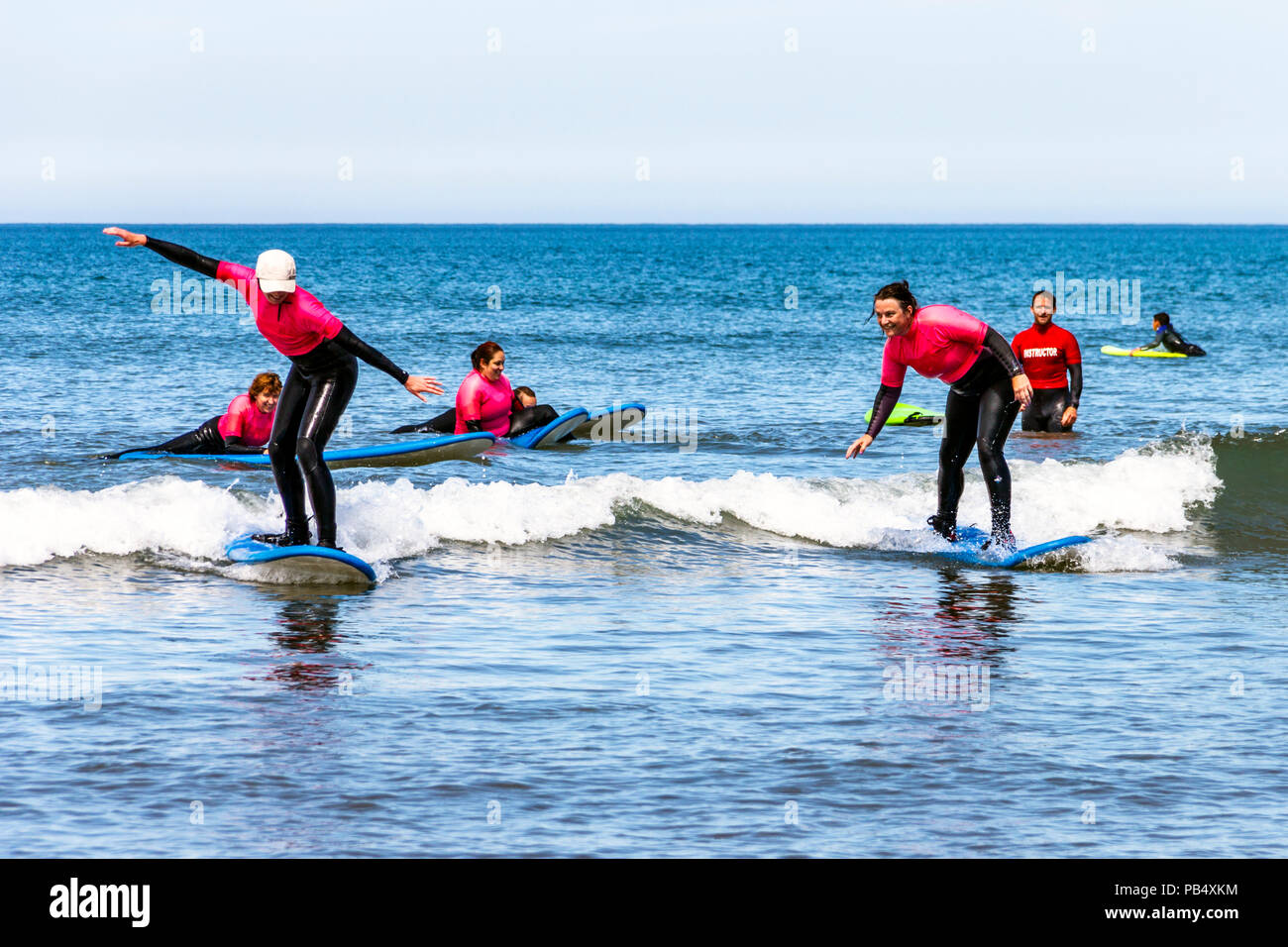 Un gruppo femminile di surfers prendendo lezioni in mare a Condino, Devon, Regno Unito Foto Stock