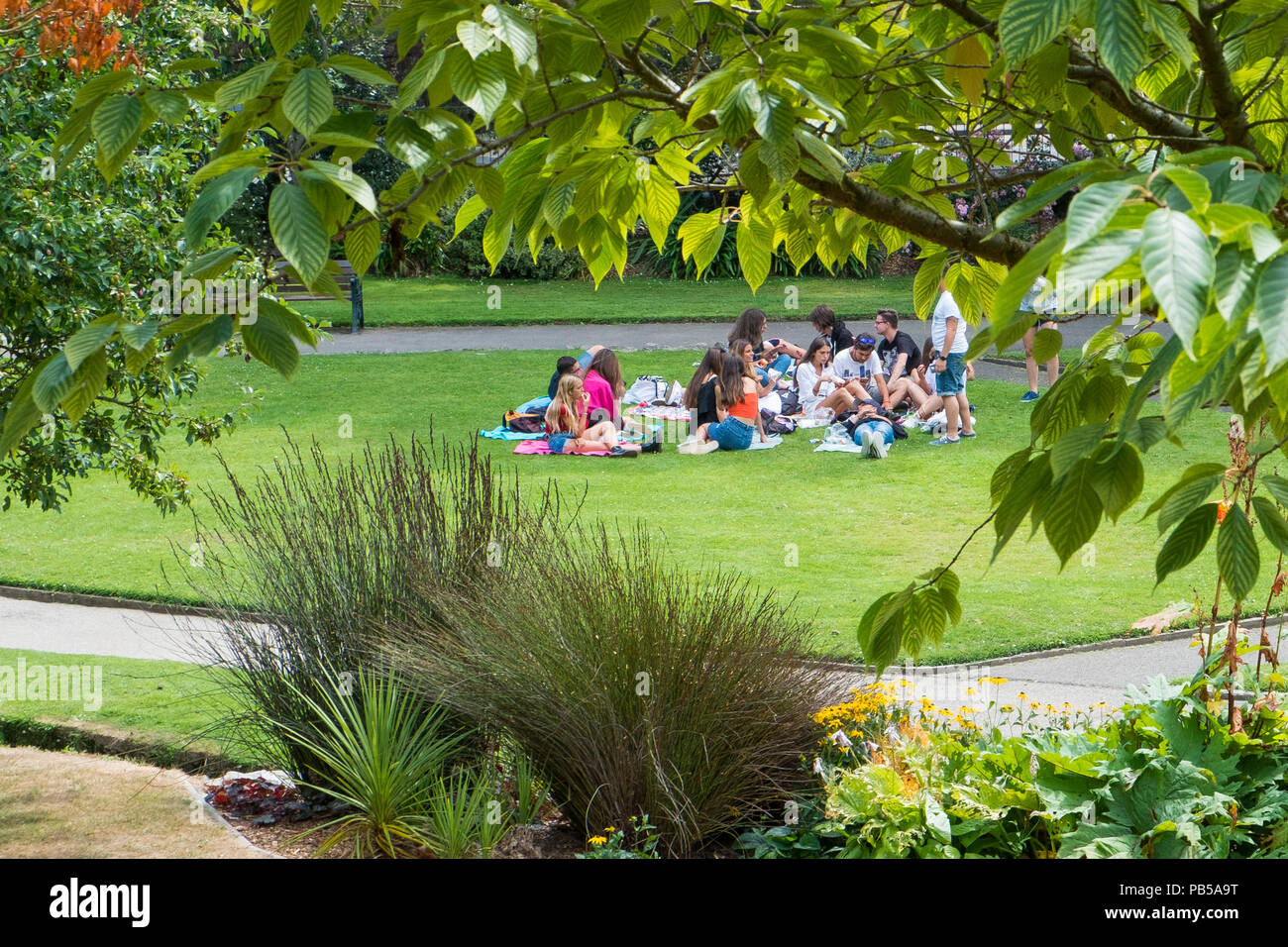 Un gruppo di giovani studenti nel rilassante giardino Trenance in Newquay Cornwall. Foto Stock