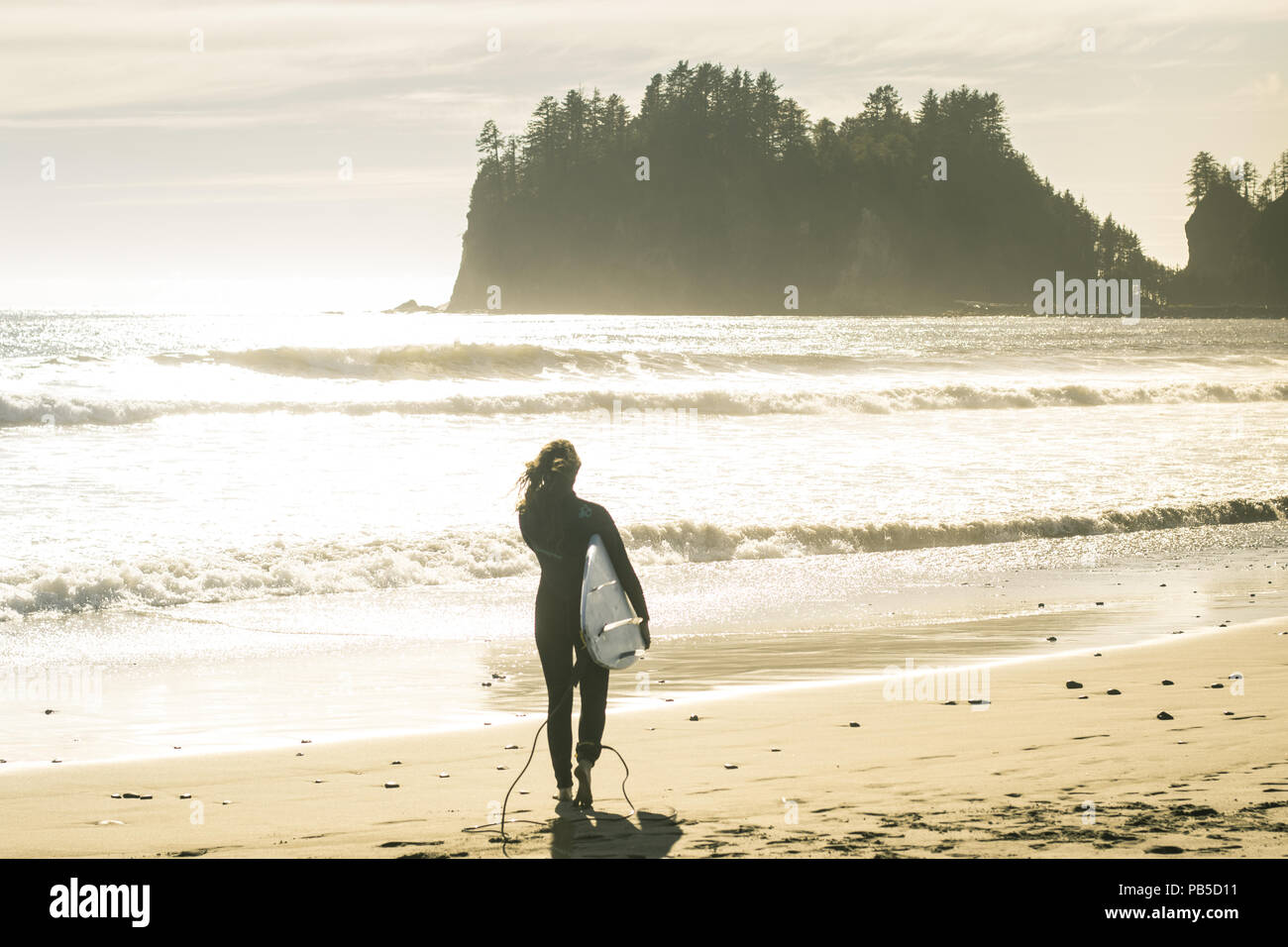 Surfista femmina a piedi per il surf durante l ora d'oro Foto Stock