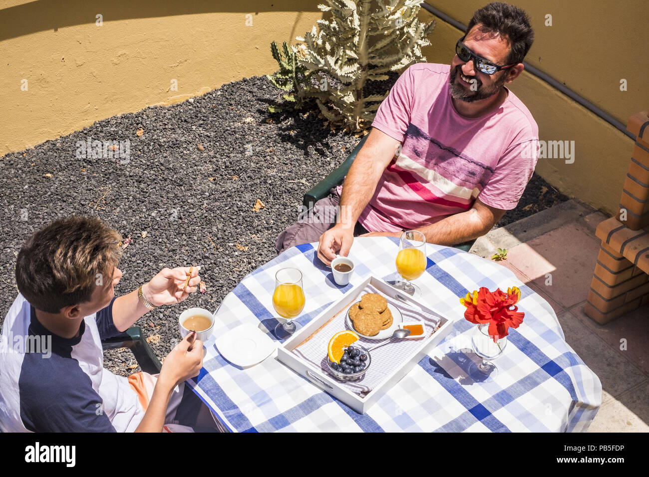 Padre e figlio caucasian persone aventi una prima colazione insieme in amicizia sotto il sole del mattino a casa. vita reale scena di persone sorridenti e di ha Foto Stock