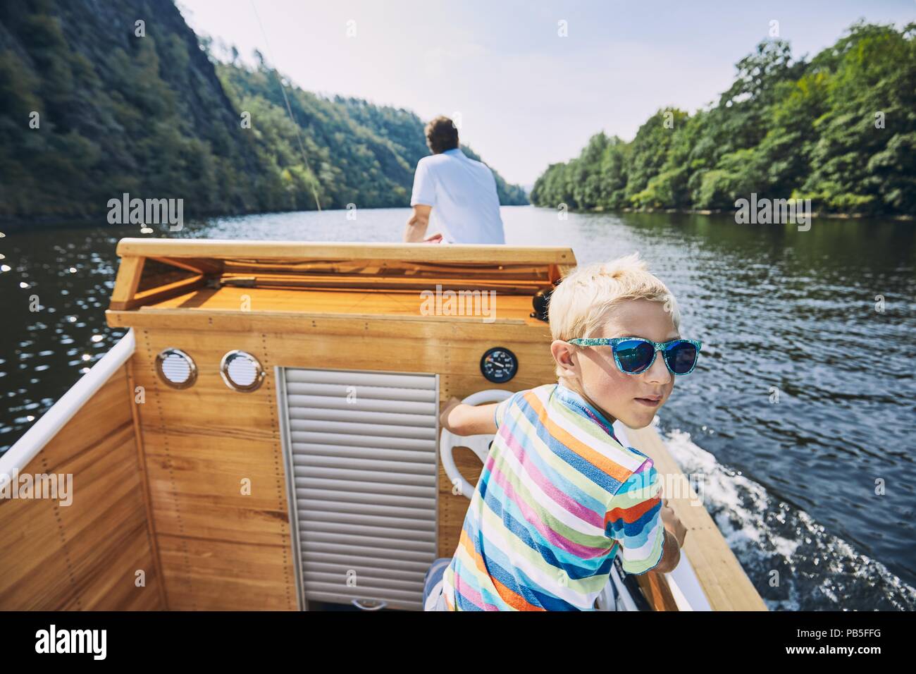 Vacanze in famiglia sul fiume. Ragazzo la guida con una barca a motore. Foto Stock