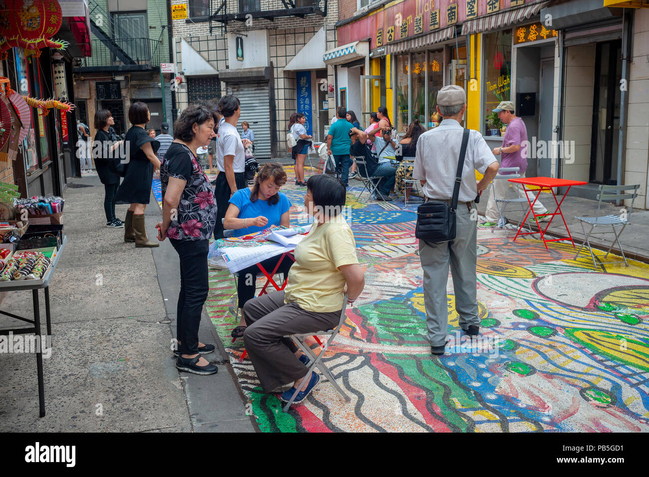 I visitatori di Doyers Street a Chinatown di New York su Mercoledì, 25 luglio 2018 godetevi il dipinto "La canzone dei draghi e fiori' dall'artista Chen Dongfan che occupa il 200 piedi lungo street. La copertina è parte del partenariato di Chinatown's sforzi per girare la stretta, pittoresca strada in una zona pedonale. (Â© Richard B. Levine) Foto Stock