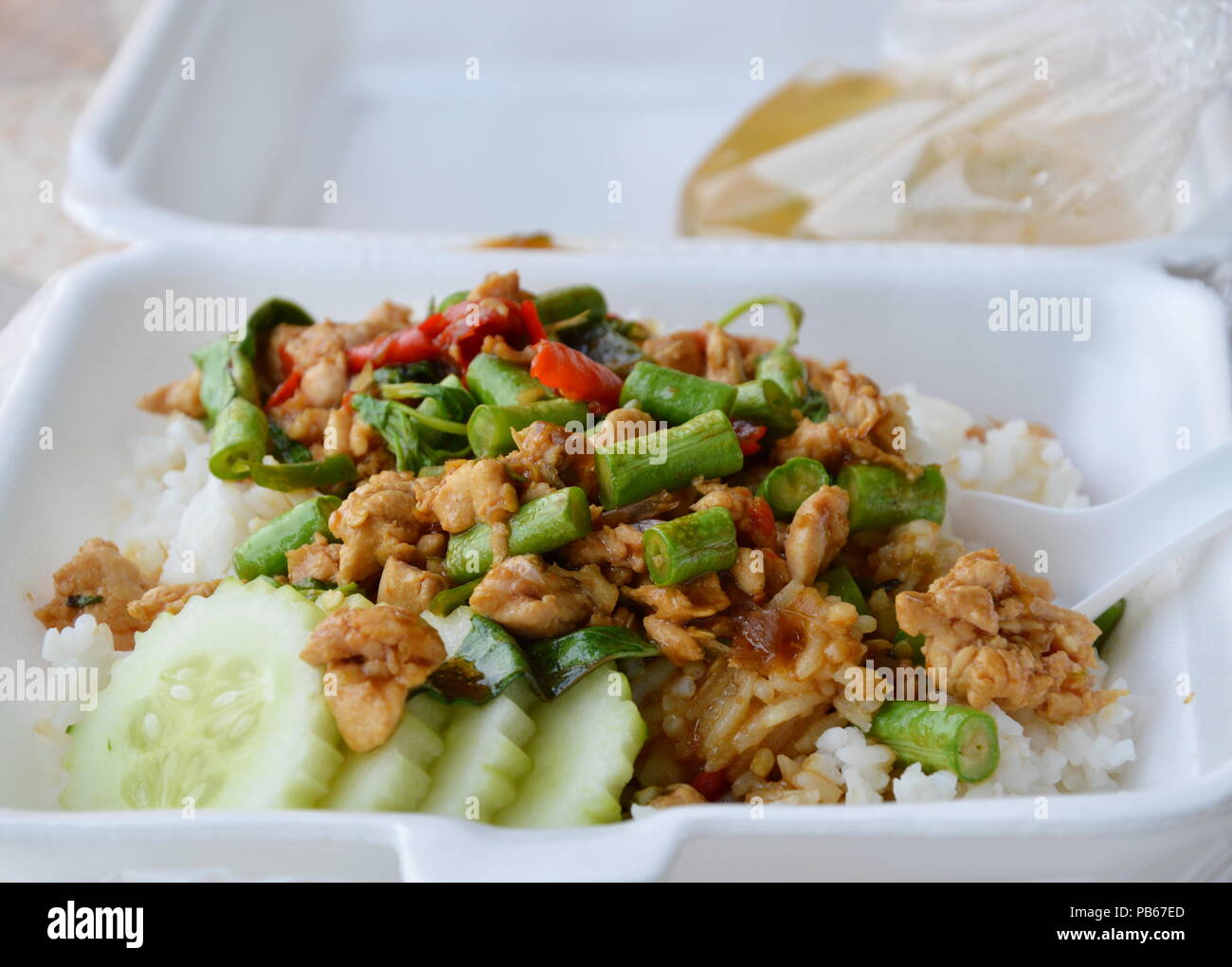 Agitare piccante pollo fritto con foglia di basilico sul riso nella casella di schiuma per portare a casa Foto Stock