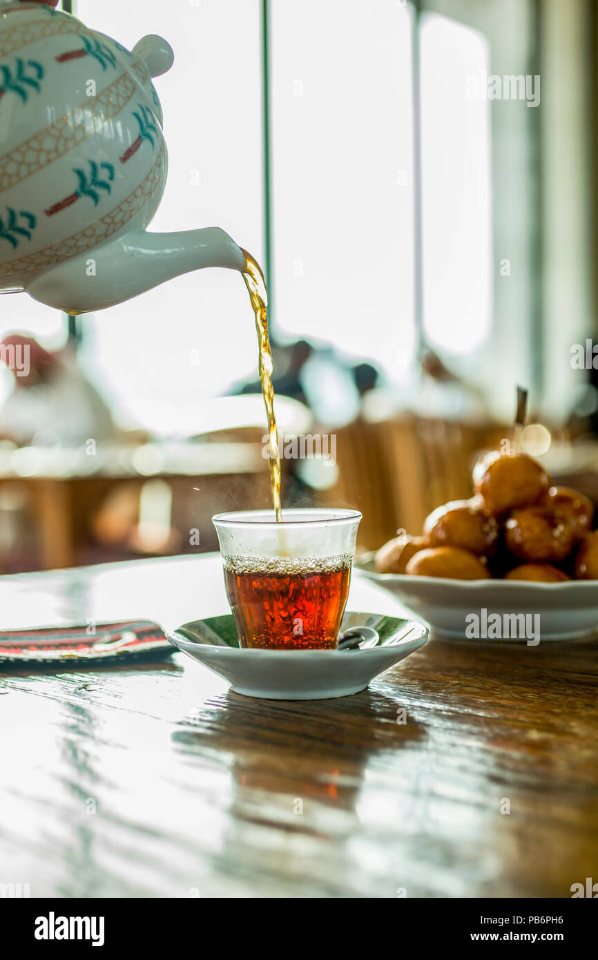 Orientale tè nero in vetro . Orientale il concetto di tè. Armudu coppa tradizionale, versando il tè nero alla tazza Foto Stock