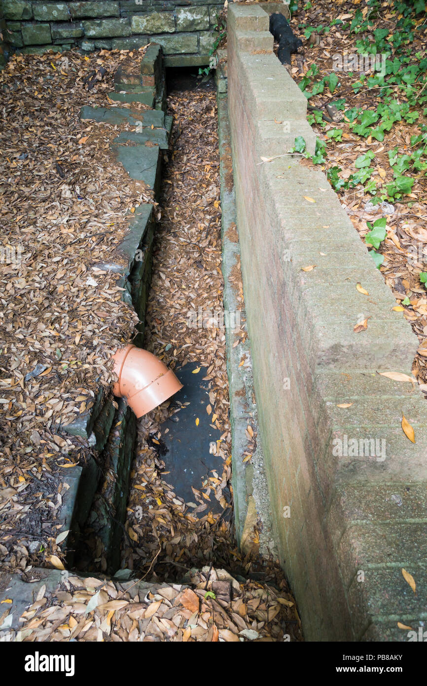 Il vecchio canale sotterraneo aperto costruita con vecchie pietre e una plastica PVC tubo fognario. Foto Stock
