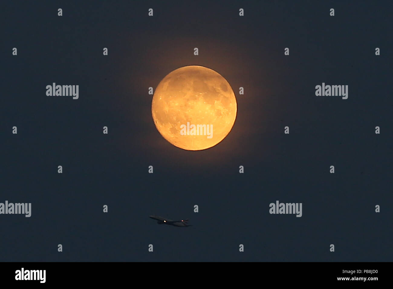 A nord di Londra. Londra. Regno Unito 26 luglio 2018 - A British Airways piano battenti sotto la luna di sangue nel nord di Londra, come il più lungo dell'eclisse lunare del secolo, fissata per venerdì 27 luglio 2018, ha già iniziato a girare il corpo celeste di un profondo colore scarlatto. La luna di sangue sarà il primo del Regno Unito, il possibilità di vedere un grande eclipse nel 2018, e secondo la NASA Luna esperti presso il Goddard Space Center, l'eclipse durerà circa un ora e 43 minuti. Credito: Dinendra Haria/Alamy Live News Foto Stock