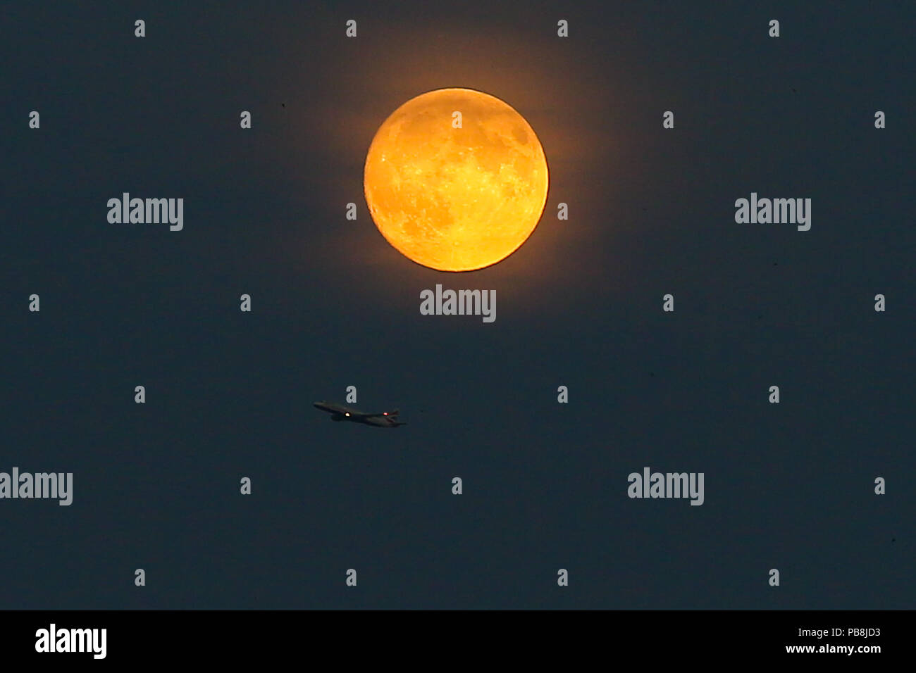 A nord di Londra. Londra. Regno Unito 26 luglio 2018 - A British Airways piano battenti sotto la luna di sangue nel nord di Londra, come il più lungo dell'eclisse lunare del secolo, fissata per venerdì 27 luglio 2018, ha già iniziato a girare il corpo celeste di un profondo colore scarlatto. La luna di sangue sarà il primo del Regno Unito, il possibilità di vedere un grande eclipse nel 2018, e secondo la NASA Luna esperti presso il Goddard Space Center, l'eclipse durerà circa un ora e 43 minuti. Credito: Dinendra Haria/Alamy Live News Foto Stock