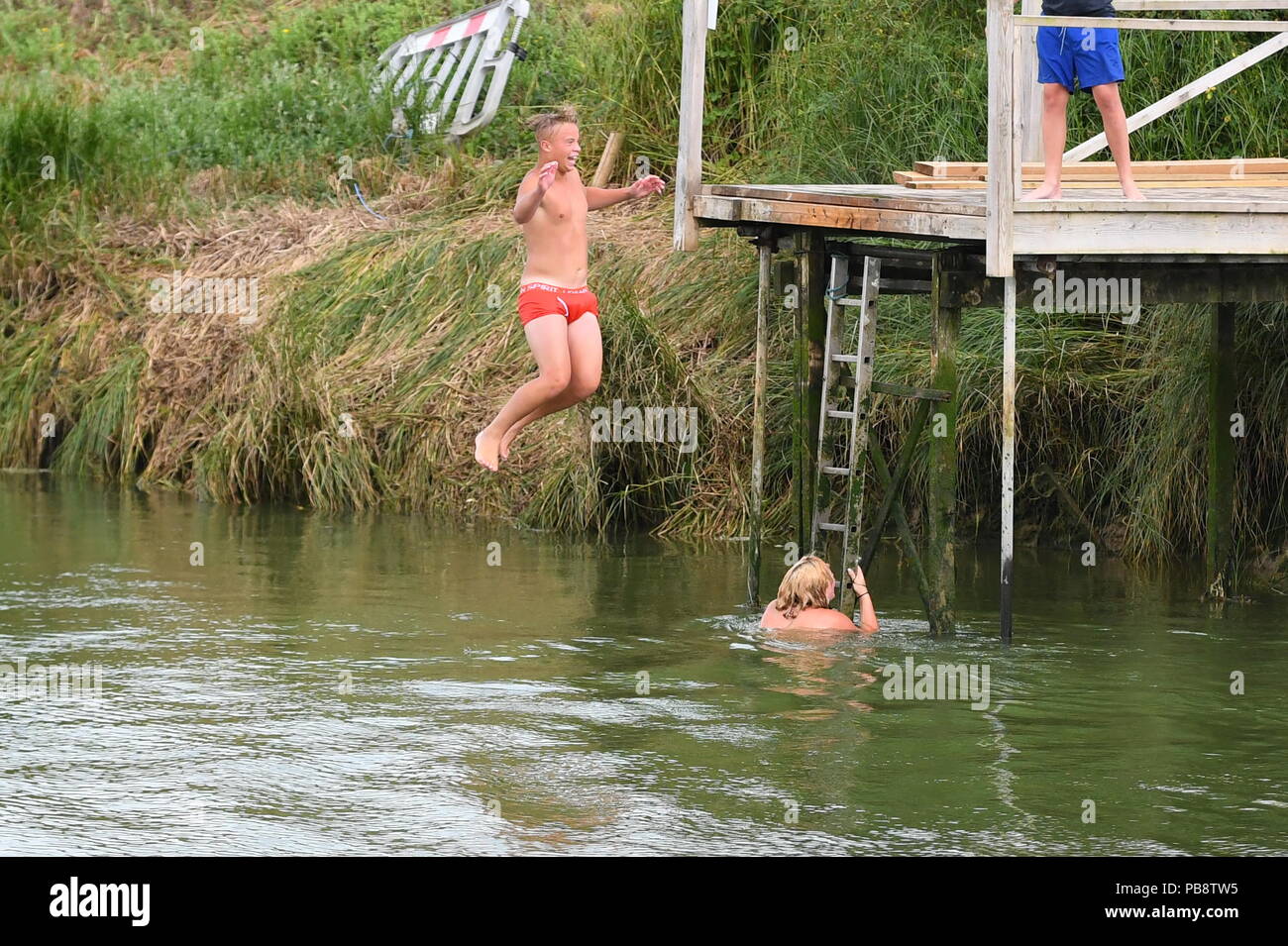 I giovani indossano pantaloncini solo salto in un fiume durante l'estate 2018 ondata di caldo nel West Sussex, in Inghilterra, Regno Unito. Foto Stock