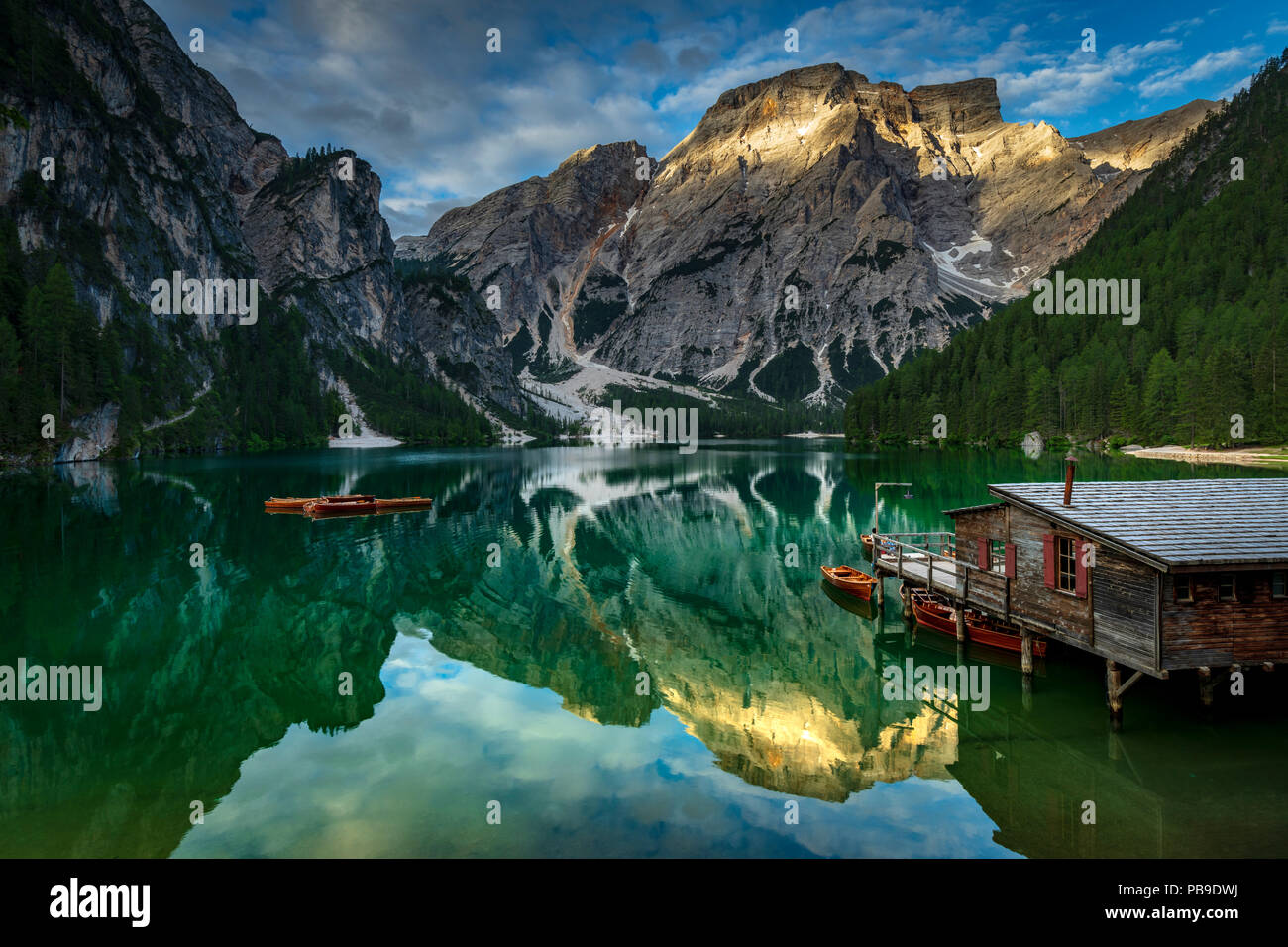 Verde lago di montagna con barche e il boathouse, Seekogel picco nel retro, acqua riflessione, il Lago di Braies, Dolomiti, Italia Foto Stock