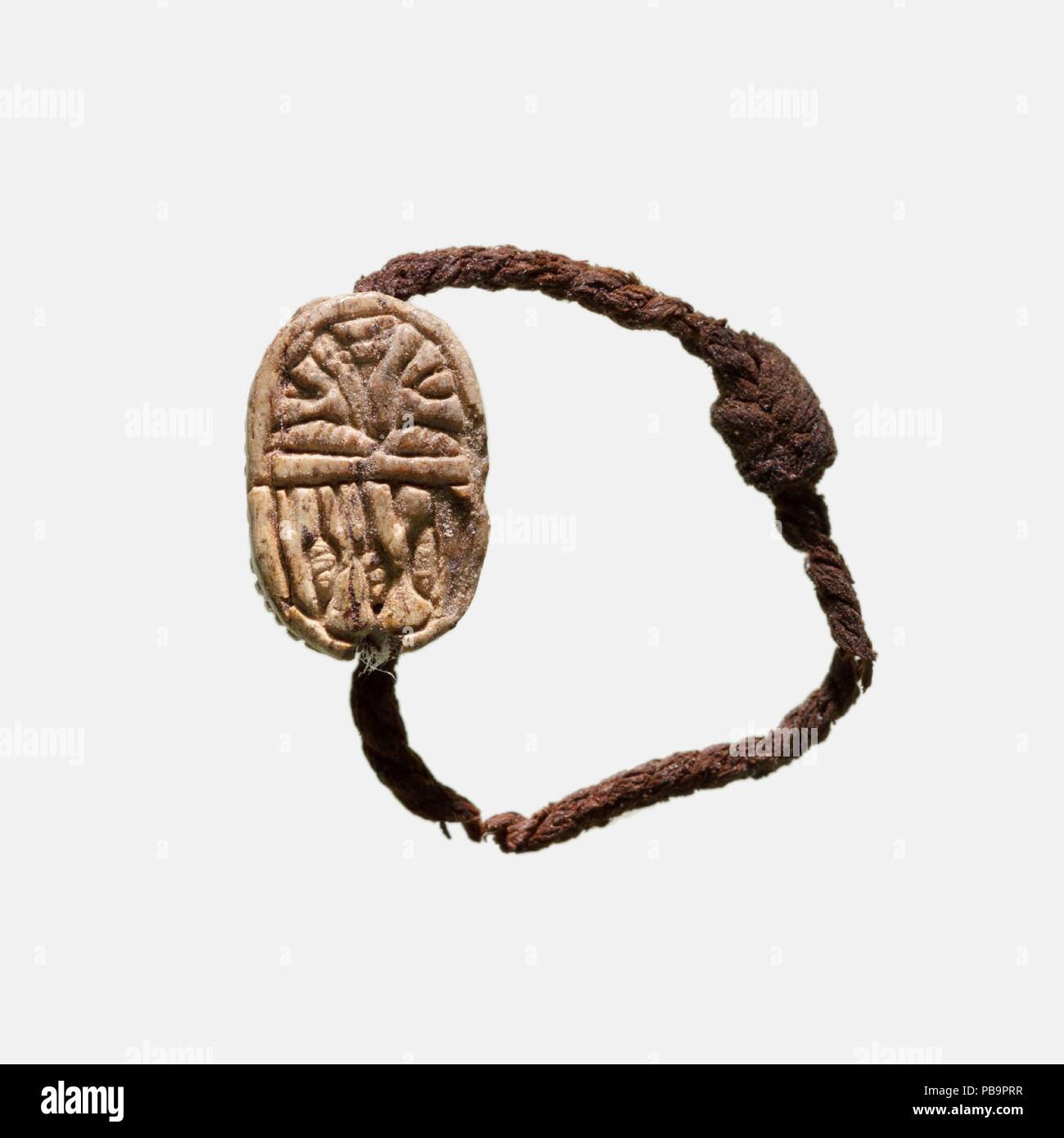 Scarabeo anello da dito. Dimensioni: SCARABEO: L. 0.8 cm (5/16 in.); W. 0,5 cm (3/16 in.); H. 0,4 cm (3/16 in.). Dynasty: Dynasty 18, presto. Regno: regno di Thutmosi I-inizio suola Thutmosi III. Data: ca. 1504-1447 A.C. Questo scarabeo, infilate sul pezzo di lino ritorto cordone, è stato trovato legato alla mano sinistra di un ragazzo di età compresa tra i nove o dieci. Il bambino era stato sepolto nella tomba di famiglia di Neferkhawet. Il dispositivo scolpito sulla base di lo scarabeo include lotus boccioli e fiori. Museo: Metropolitan Museum of Art di New York, Stati Uniti d'America. Foto Stock