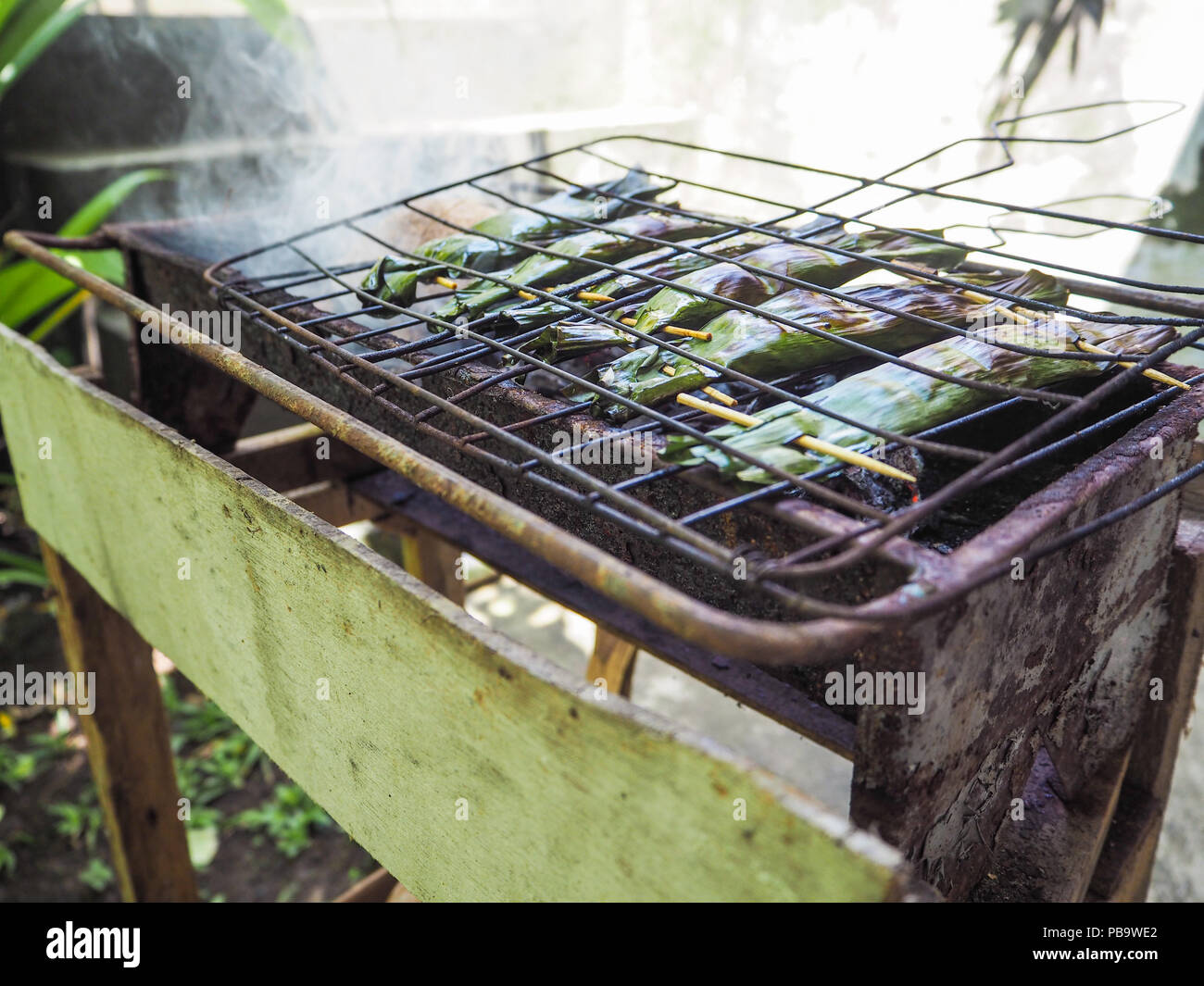 Pesce in foglie di banano ( chiamato Ikan Pepes) grigliare su un barbeque, Ubud, Bali Foto Stock