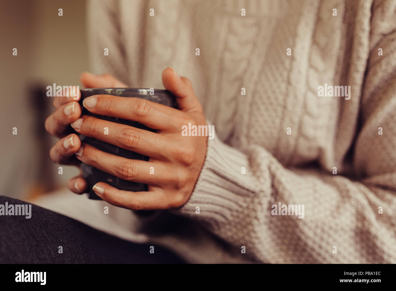 Close up femmina con una tazza di tè. Ritagliato colpo di donna con il tè del mattino a letto. Concentrarsi sulle mani tenendo una tazza di tè. Foto Stock