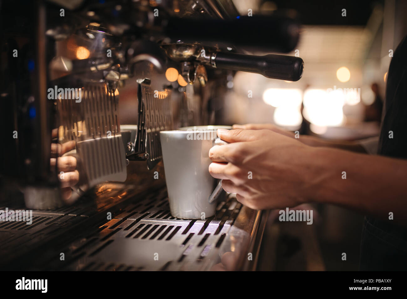Chiusura del barista tenendo una tazza sotto la macchina per il caffè. Femmina lavoratore cafe la preparazione di caffè in macchina. Foto Stock