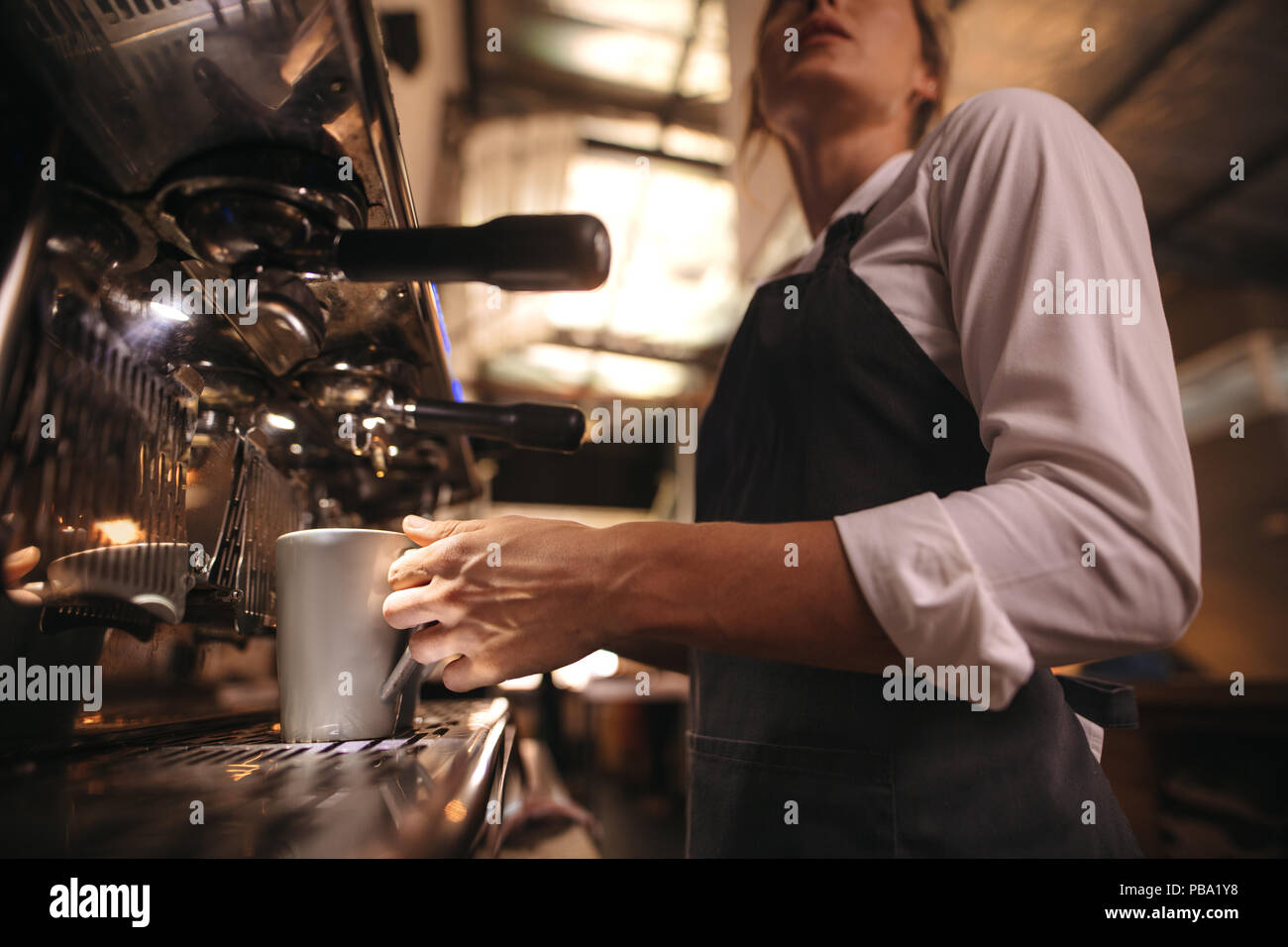 Donna che lavorano in cafe indossando il grembiule facendo un caffè nella macchina. Barista il caffè sulla macchina per il caffè macchina. Foto Stock