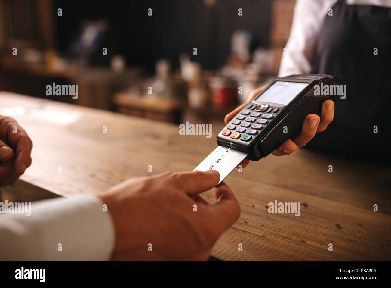 Il cliente inserisce la sua carta di credito nella macchina per il pagamento presso il cafe. Il cliente paga per loro ordine con una carta di credito in un caffè con il barista hol Foto Stock