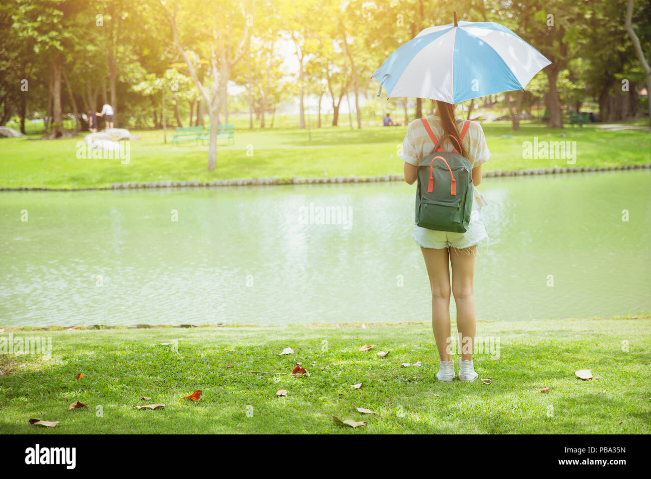 Girl Teen nel parco in piedi con ombrello torna visualizza sole luminoso tono vintage Foto Stock