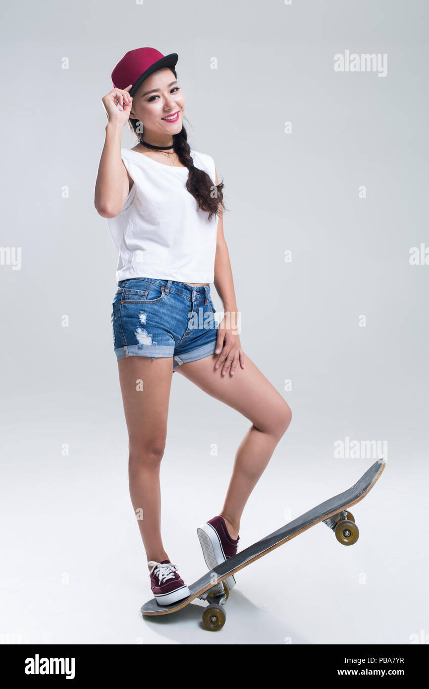 Allegro giovane donna cinese lo skateboard Foto Stock