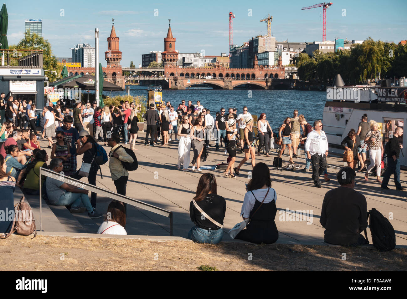 Persone, rilassanti passeggiate sul fiume Spree bank, Berlino skyline, Oberbaum Bridge e il fiume Sprea panorama Foto Stock