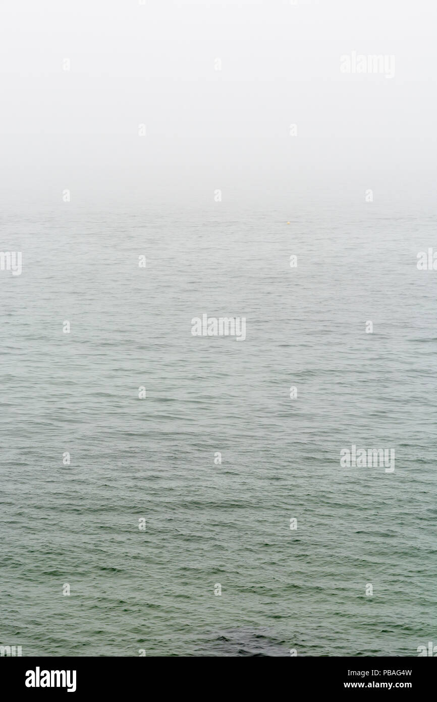 Appartamento mare grigio con wavelets scomparendo nella nebbia. Foto Stock