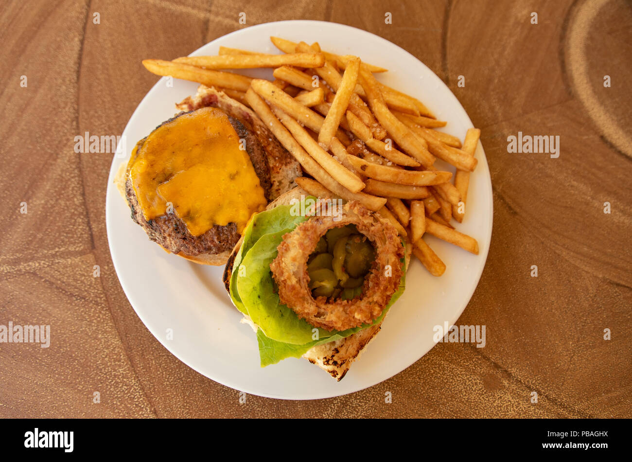 Cheeseburger con patatine fritte e insalata su piastra bianca Foto Stock