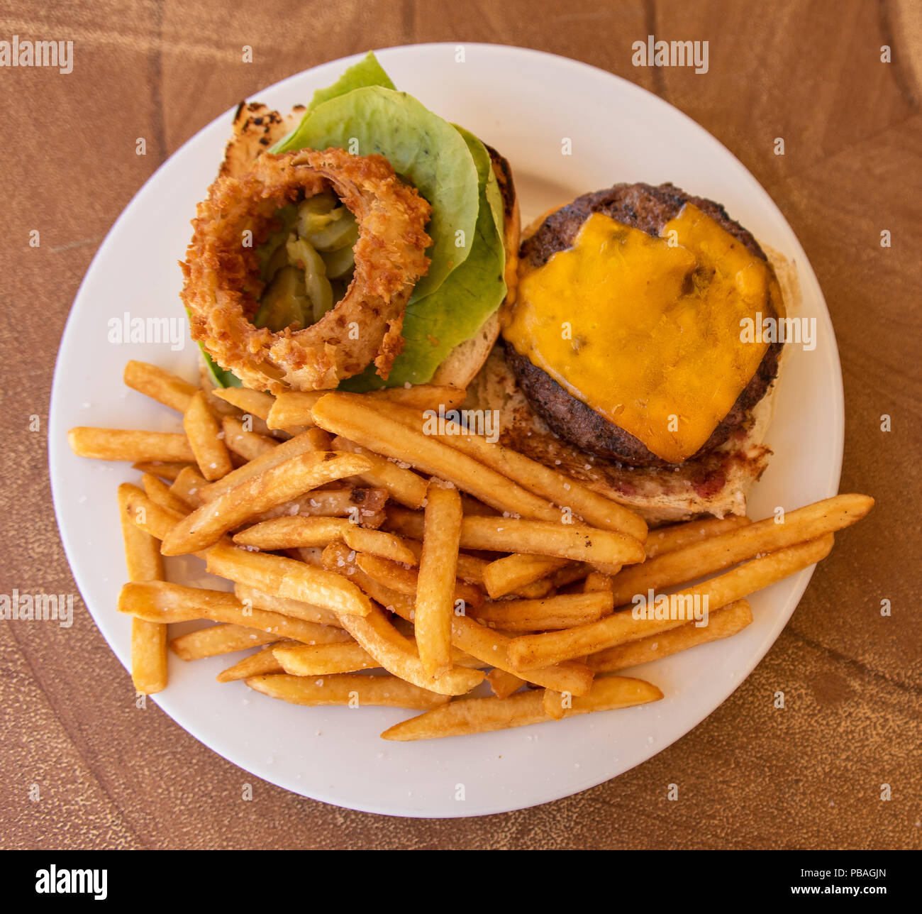 Cheeseburger con patatine fritte e insalata su piastra bianca Foto Stock