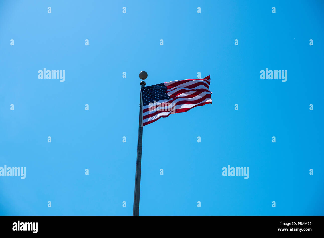 Bandiera americana che fluttua nel vento su un brillante sfondo blu cielo Foto Stock