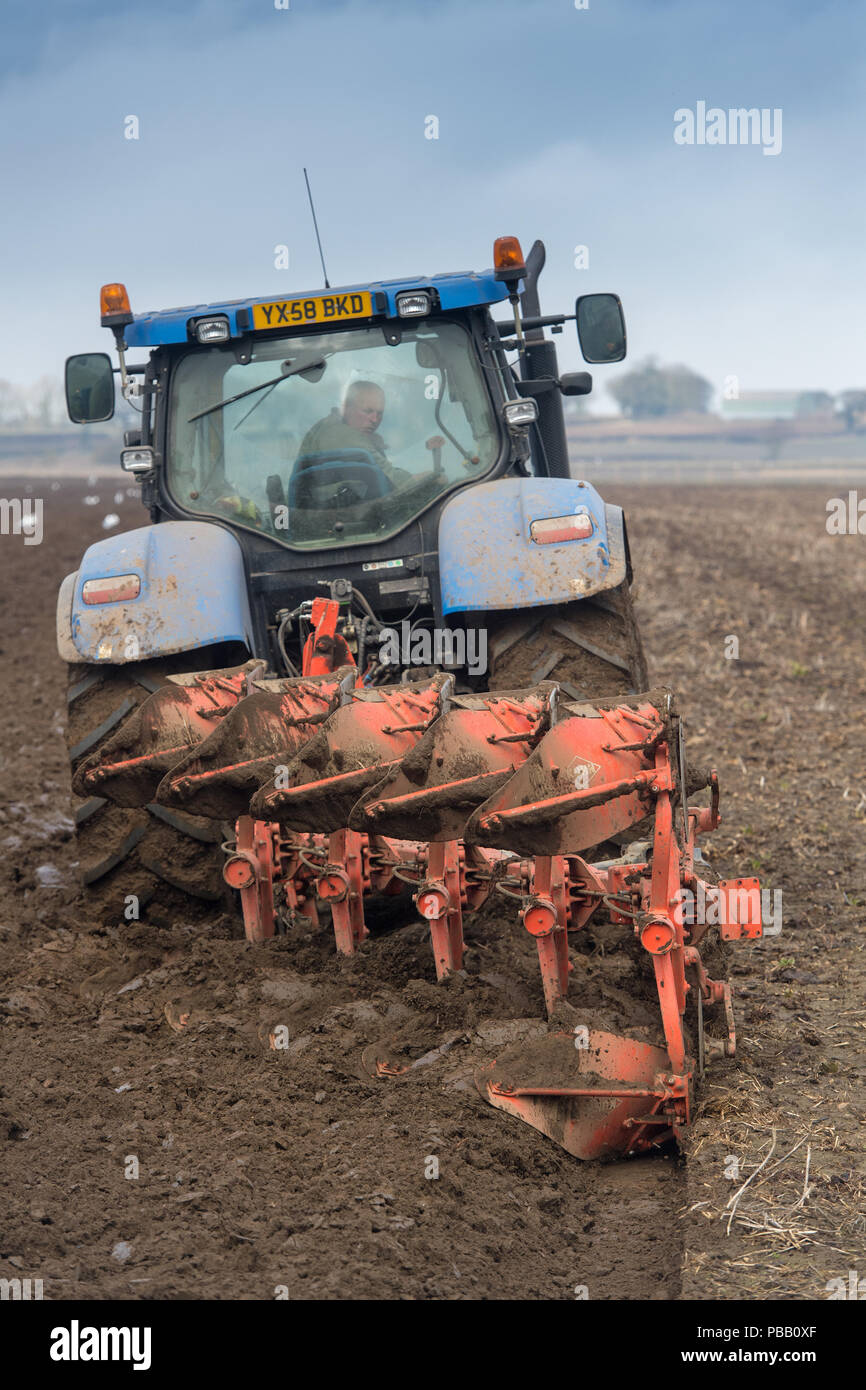 L'aratura di un campo con una New Holland T7030 e un solco 5 reversibile aratro Kuhn, voce di distanza. North Yorkshire, Regno Unito. Foto Stock