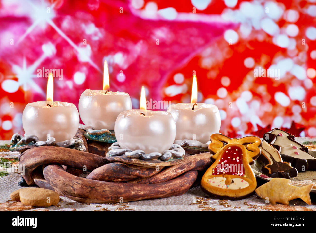 Corona di Avvento con candele accese su sfondo rosso Foto Stock