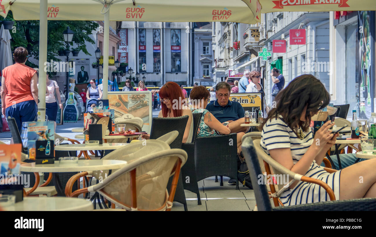 Zemun, Belgrado, Serbia, Maggio 2018 - Gli ospiti su un cafe bar terrazza ossessivamente in impegno con il loro smartphone non avente alcun riguardo per le loro frazioni Foto Stock