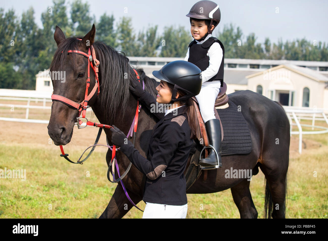 Giovani cinesi madre figlia di insegnamento di equitazione Foto Stock