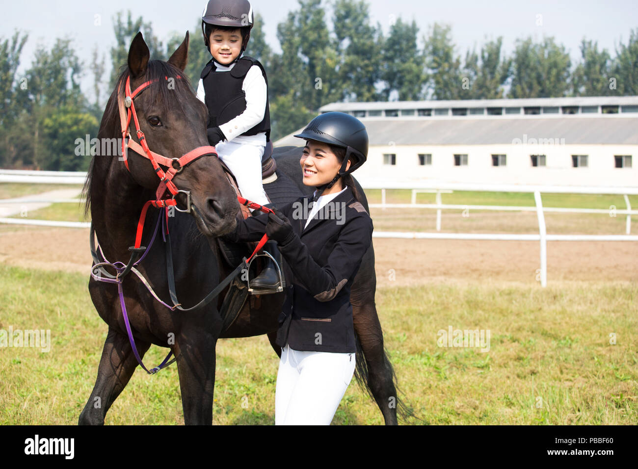 Giovani cinesi madre figlia di insegnamento di equitazione Foto Stock