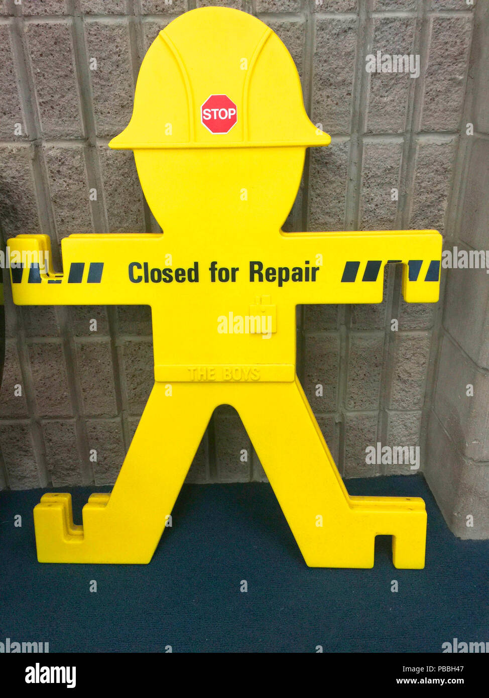 Segni di colore giallo di un uomo in piedi con un casco sono impilati fino nella zona di partenza di un aeroporto canadese. Questi segni sono ampiamente utilizzati per indicare aree Foto Stock