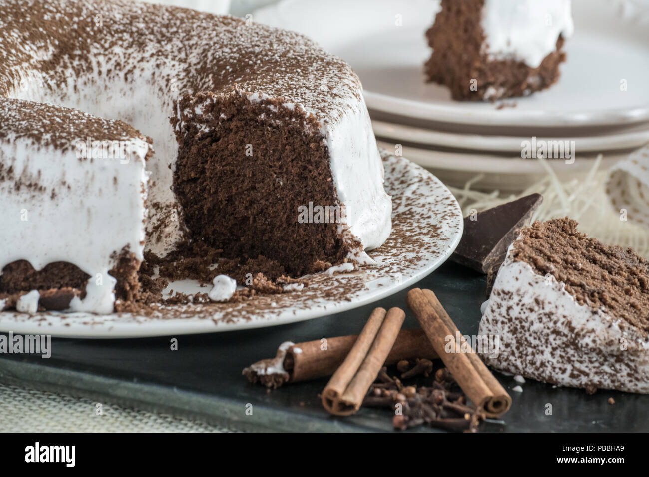 Il cioccolato Devil's Food Cake con glassa di marshmallow. Dessert fatti in casa closeup view, spolverata di cacao in polvere. Foto Stock