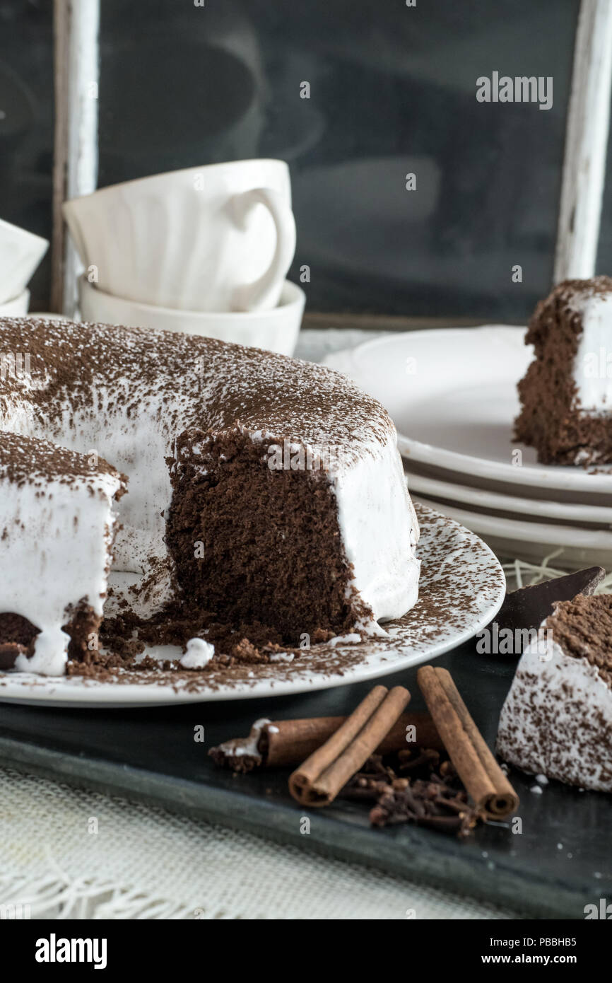 Il cioccolato Devil's Food Cake con glassa di marshmallow. Dessert fatti in casa closeup view, spolverata di cacao in polvere. Foto Stock
