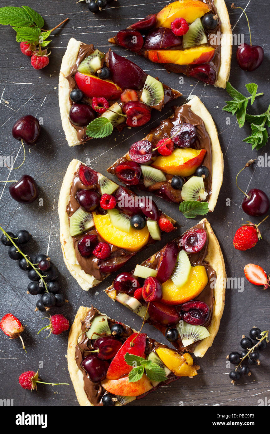 Pizza menu. Frutta estiva berry pizza con impasto di cioccolato. Vitamina dessert. Vista superiore piatta sullo sfondo dei laici. Foto Stock