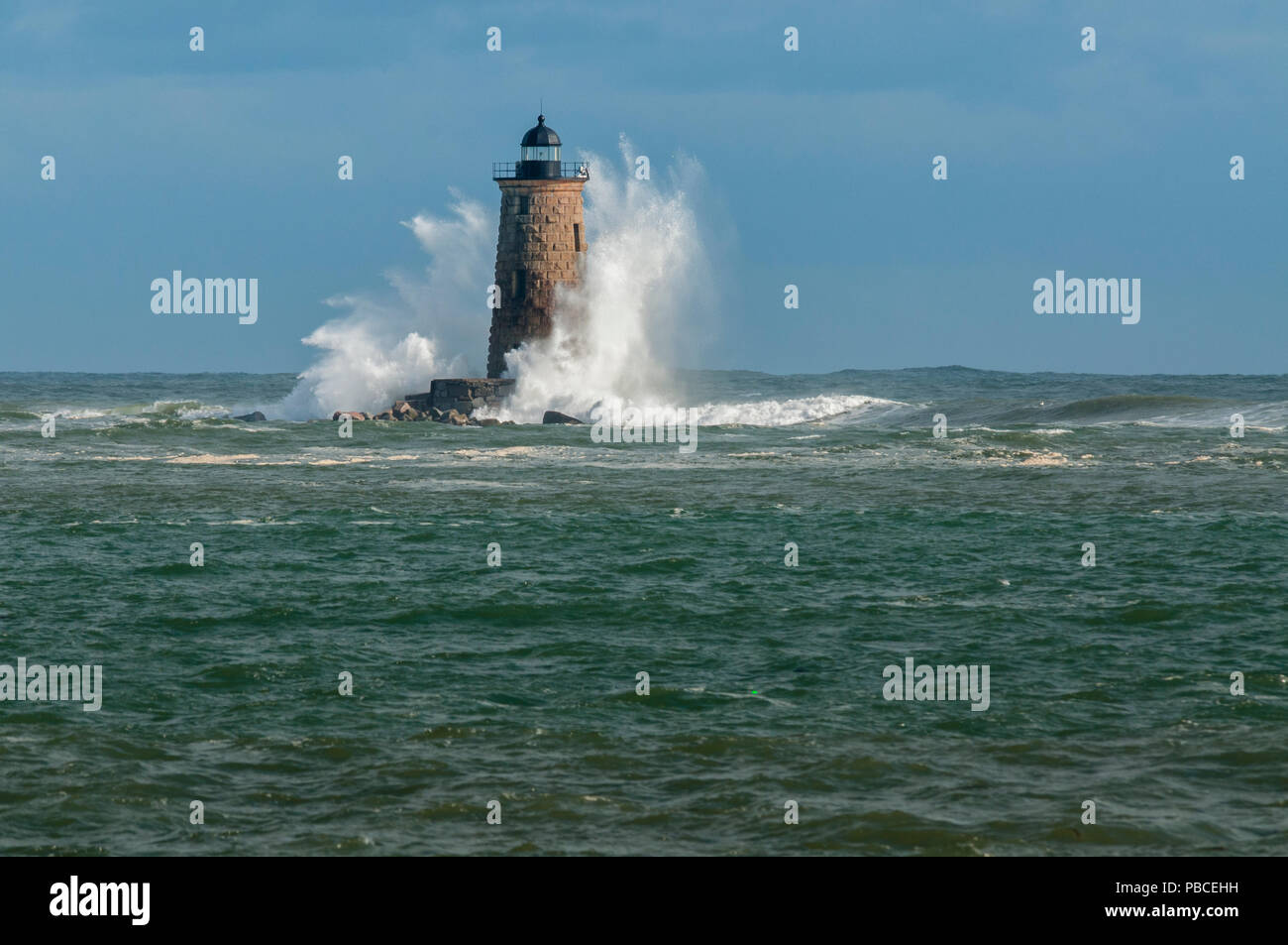 Potenti onde rare coprono una pietra torre faro nel Maine. Foto Stock