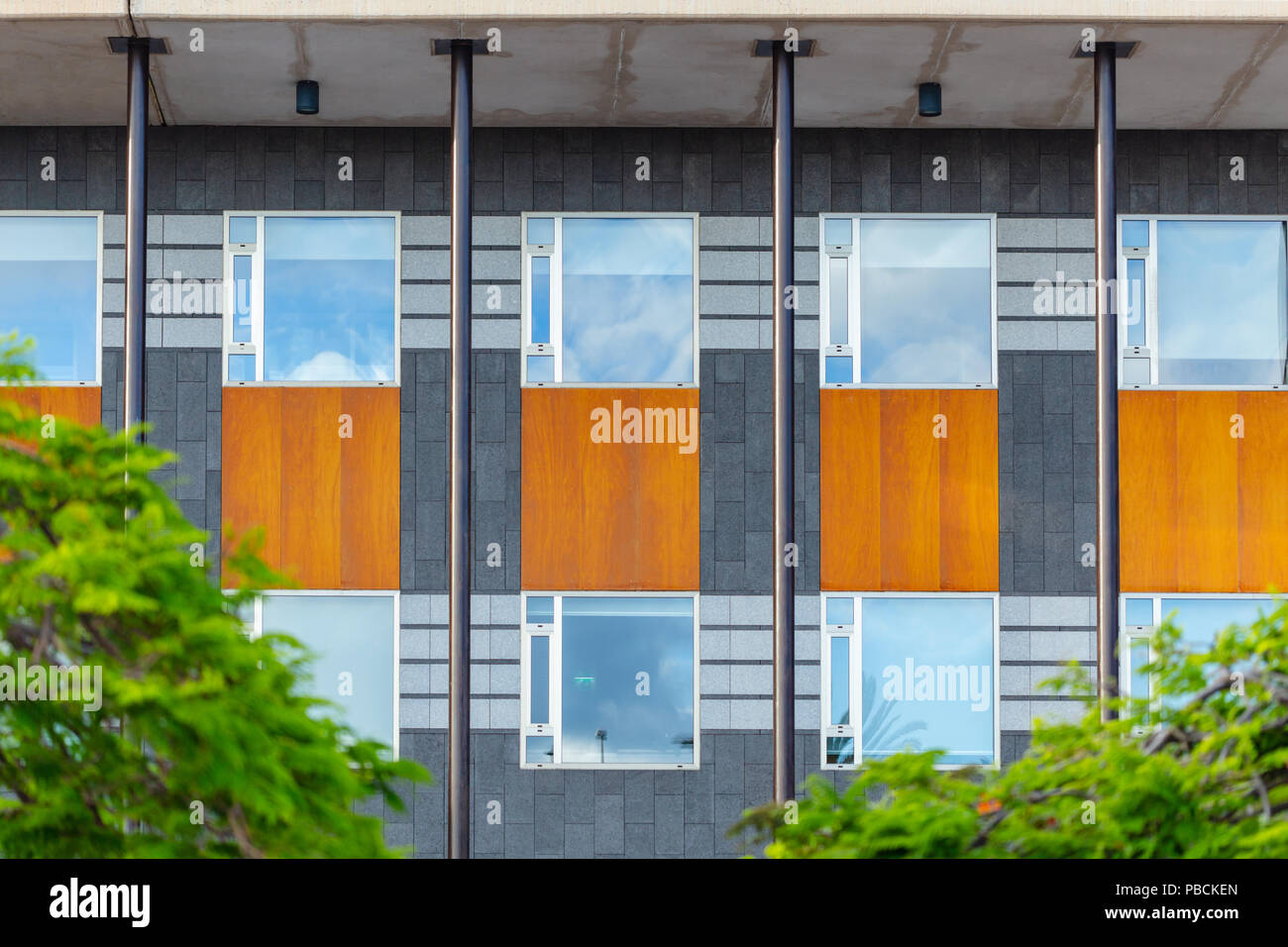 Facciata di edificio uffici, ripetendo windows, poli in acciaio e trave di legno. Architettura moderna. Foto Stock