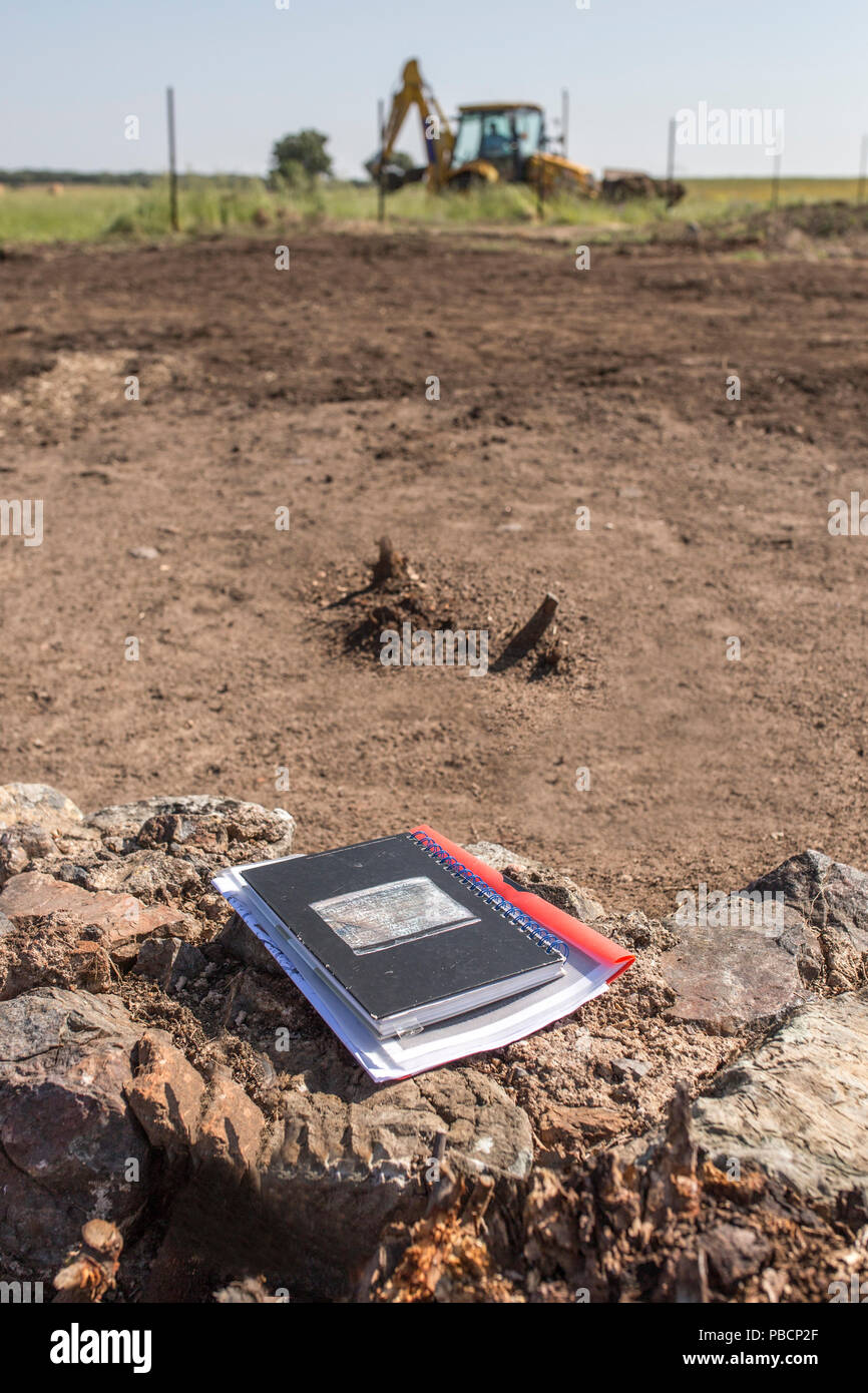 Archeologo notebook sul sito dello scavo. Escavatore a cucchiaio rovescio in basso Foto Stock