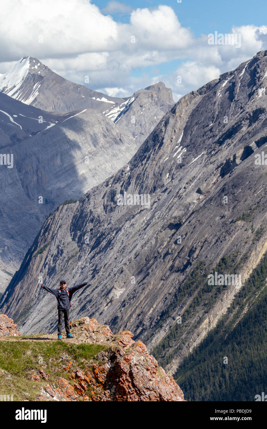 Un adolescente escursionista permanente al bordo della Parker Ridge crest sulla Icefields Parkway nel Parco Nazionale di Jasper con le Montagne Rocciose Canadesi in background. Foto Stock