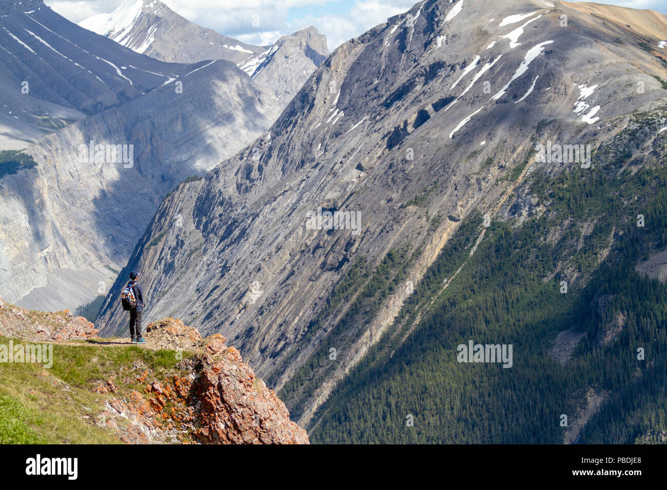 Un adolescente escursionista permanente al bordo della Parker Ridge crest sulla Icefields Parkway nel Parco Nazionale di Jasper con le Montagne Rocciose Canadesi in background. Foto Stock