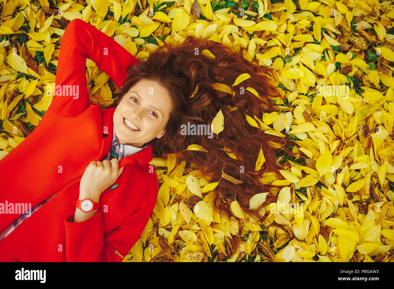 Sorridente womn Foglie di autunno nei capelli Foto Stock