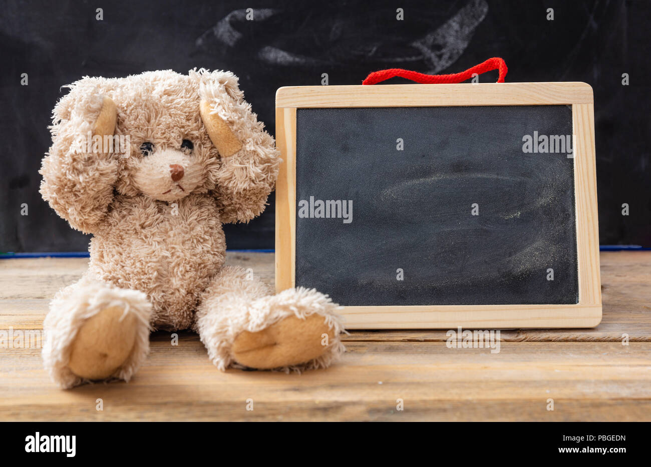 Il bullismo a scuola o difficoltà di apprendimento del concetto. Orsacchiotto di peluche che coprono le orecchie e una lavagna vuota, lo spazio per il testo Foto Stock
