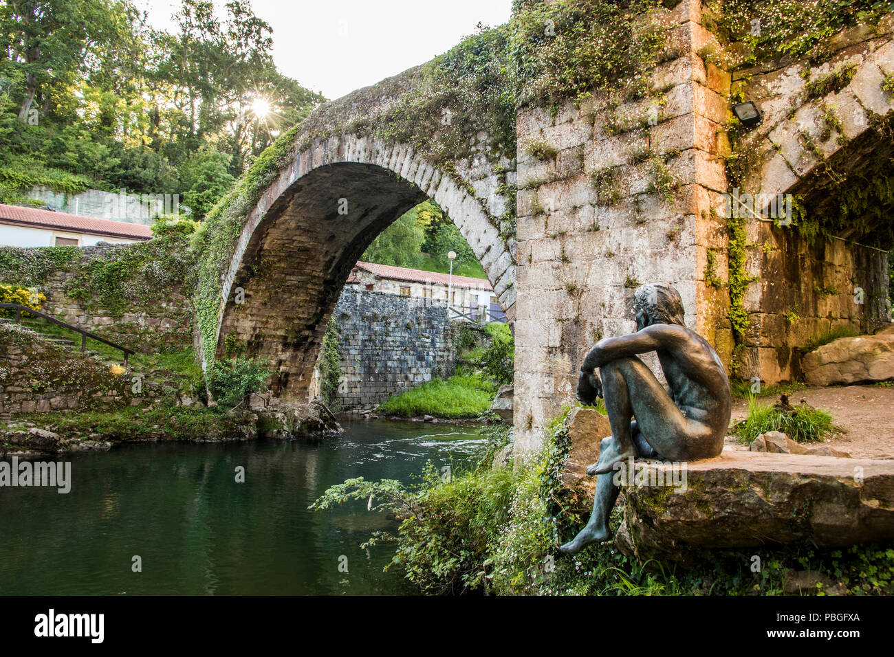 Lierganes, Spagna. Il Puente Viejo (Ponte Vecchio), con la statua del Hombre Pez (uomo-pesce), un ente che appartiene alla mitologia della Cantabria, Foto Stock